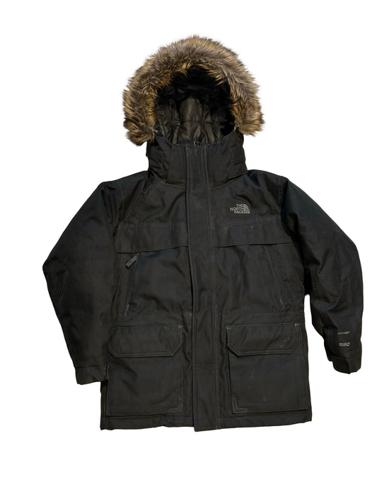 The North Face isolerad parkas i svart. Jackan har en huva med pälskant och är fotograferad platt mot en vit bakgrund.