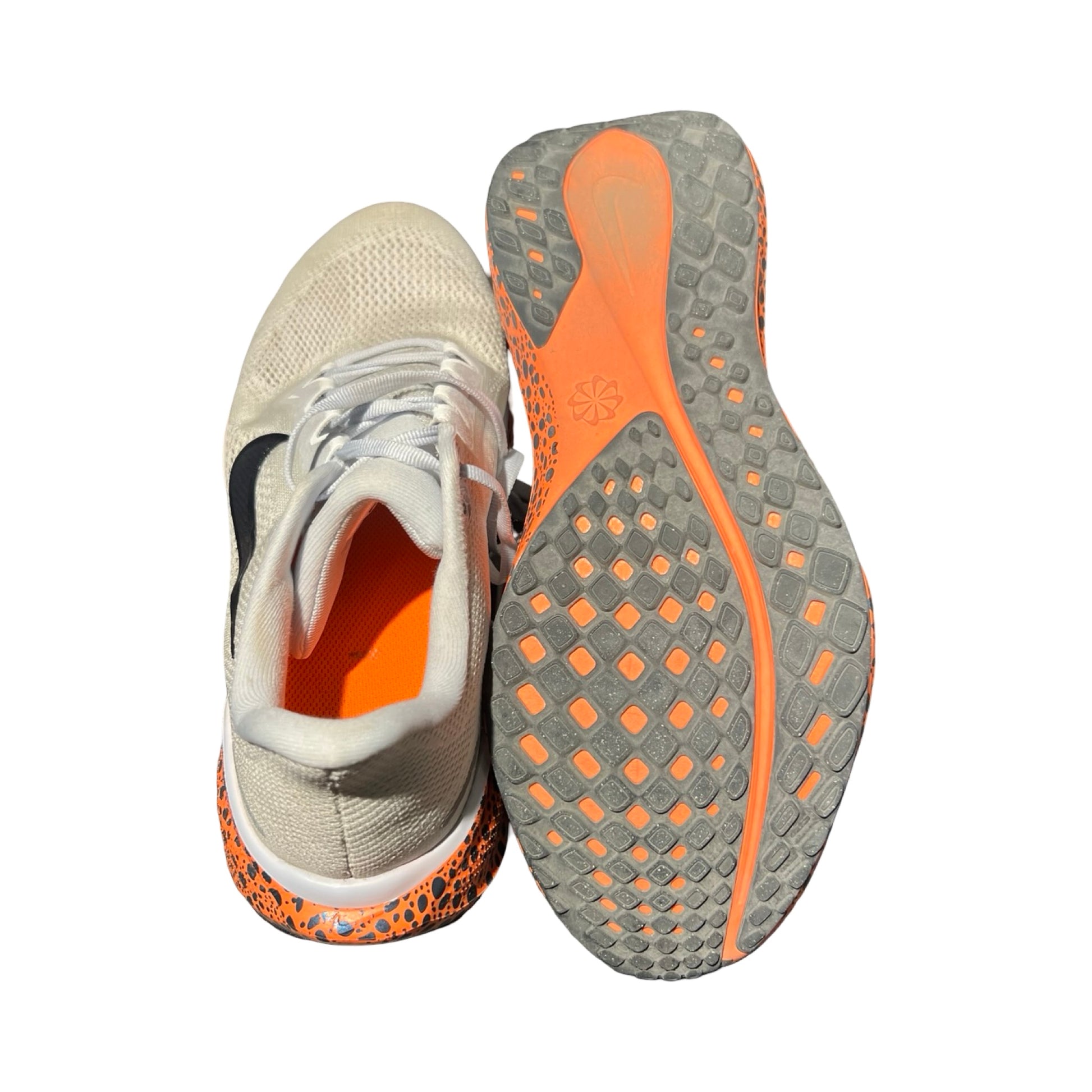 Nike Zoomx träningsskor för herr i ljusgrått. Skorna har vita snören och orange detaljer och är fotograferade mot en vit bakgrund, där ena skon visar undersidan.