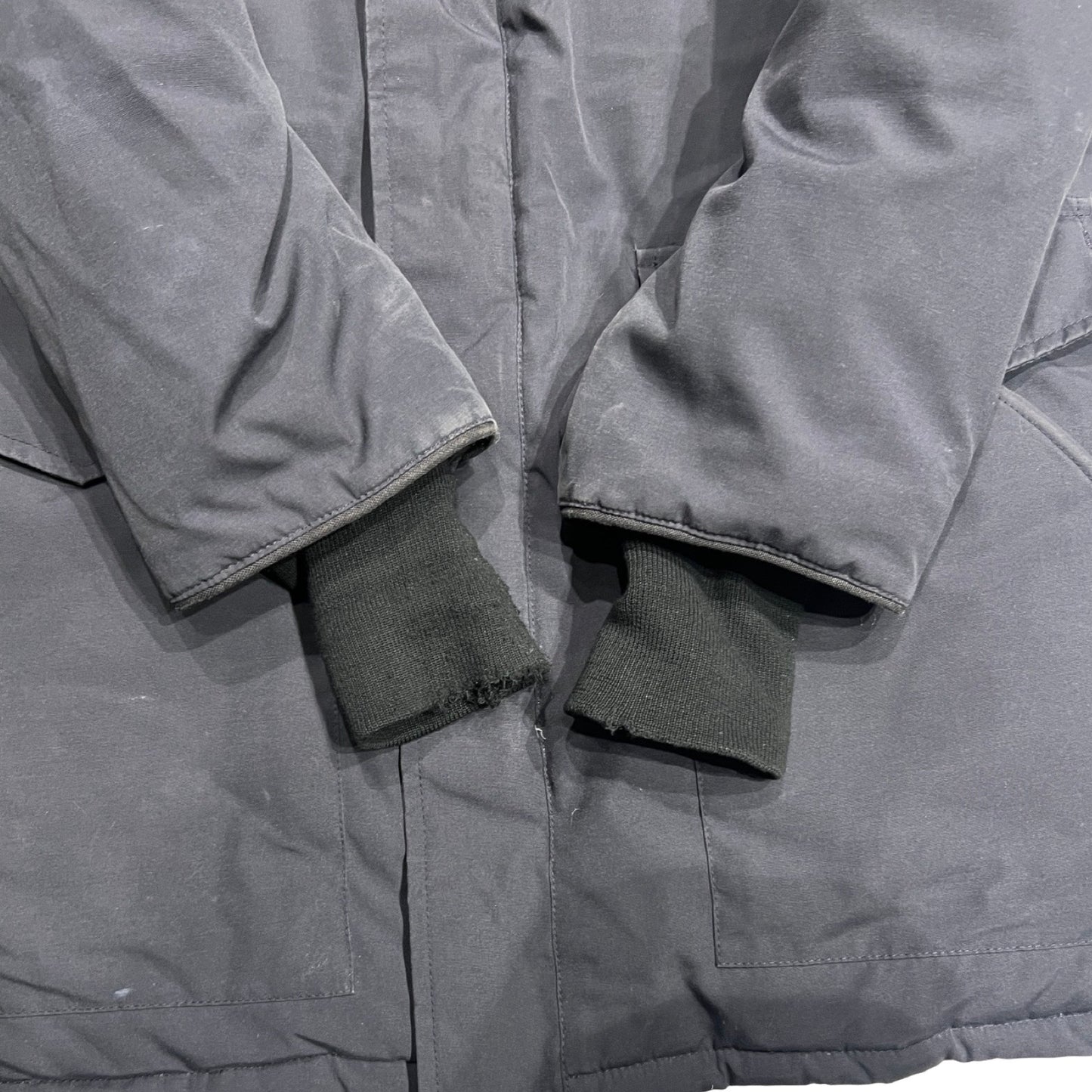 Närbild på ärmsluten av Canada Goose Heli Arctic dunjacka för herr i svart som visar slitage på muddarna.