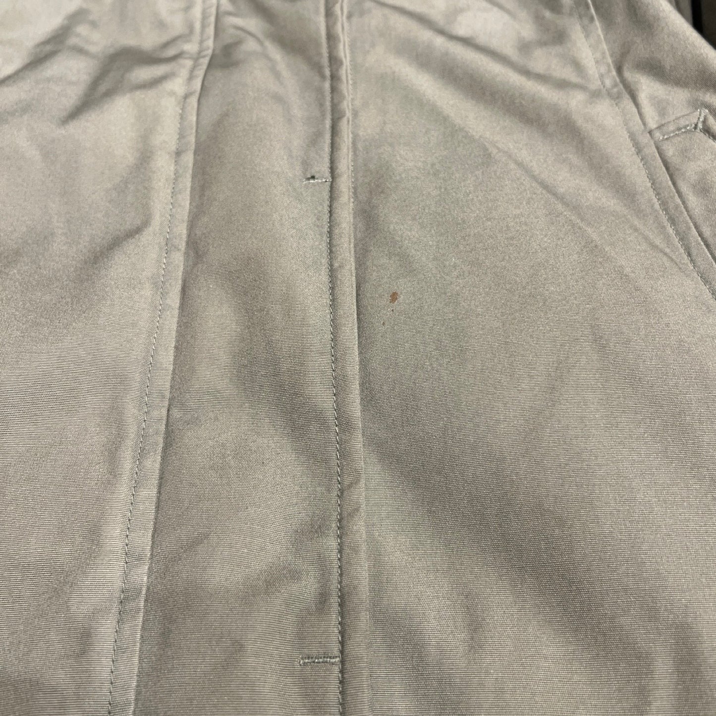 Närbild på en fläck på Peak Performance Down Parka dunjacka för dam i grönt.