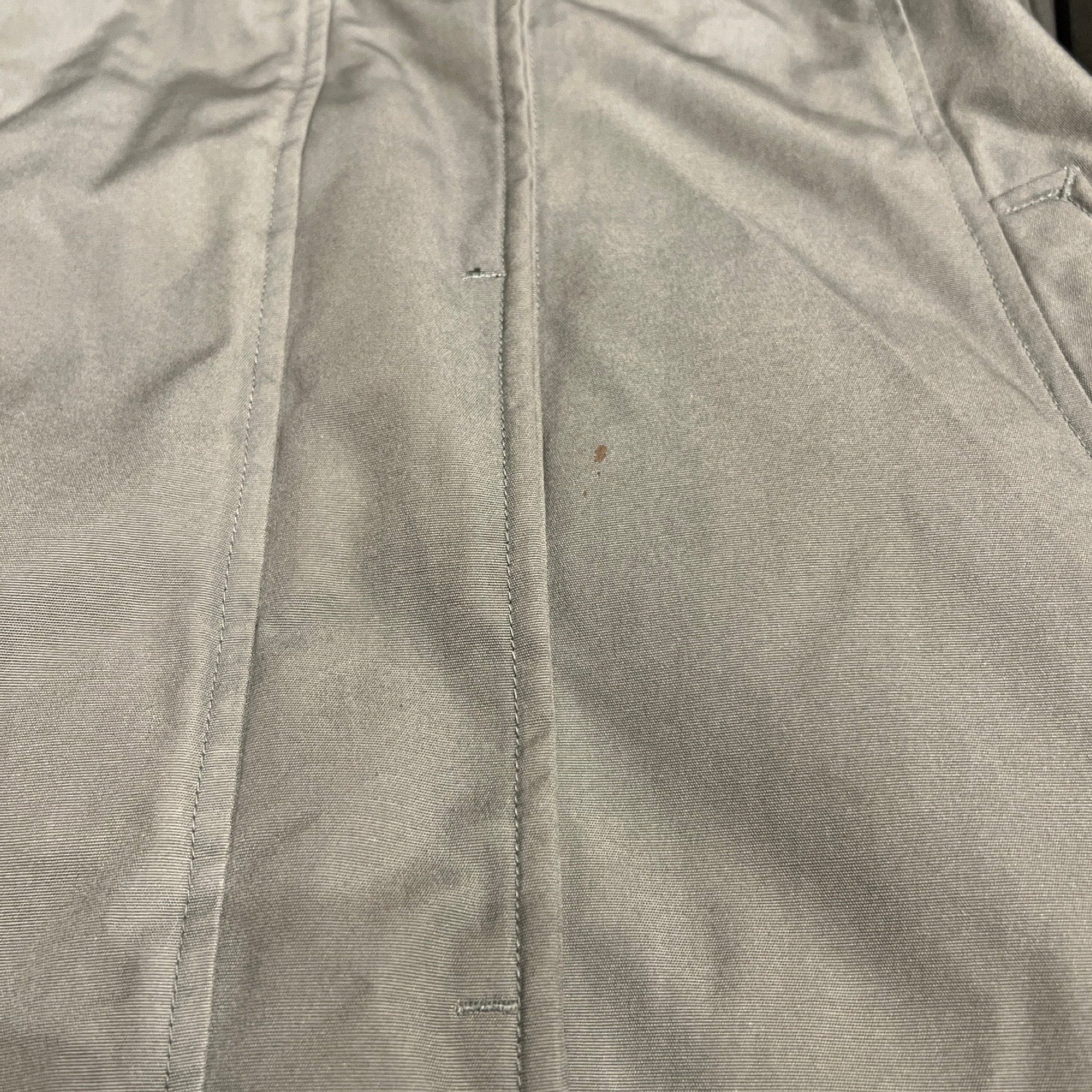 Närbild på en fläck på Peak Performance Down Parka dunjacka för dam i grönt.