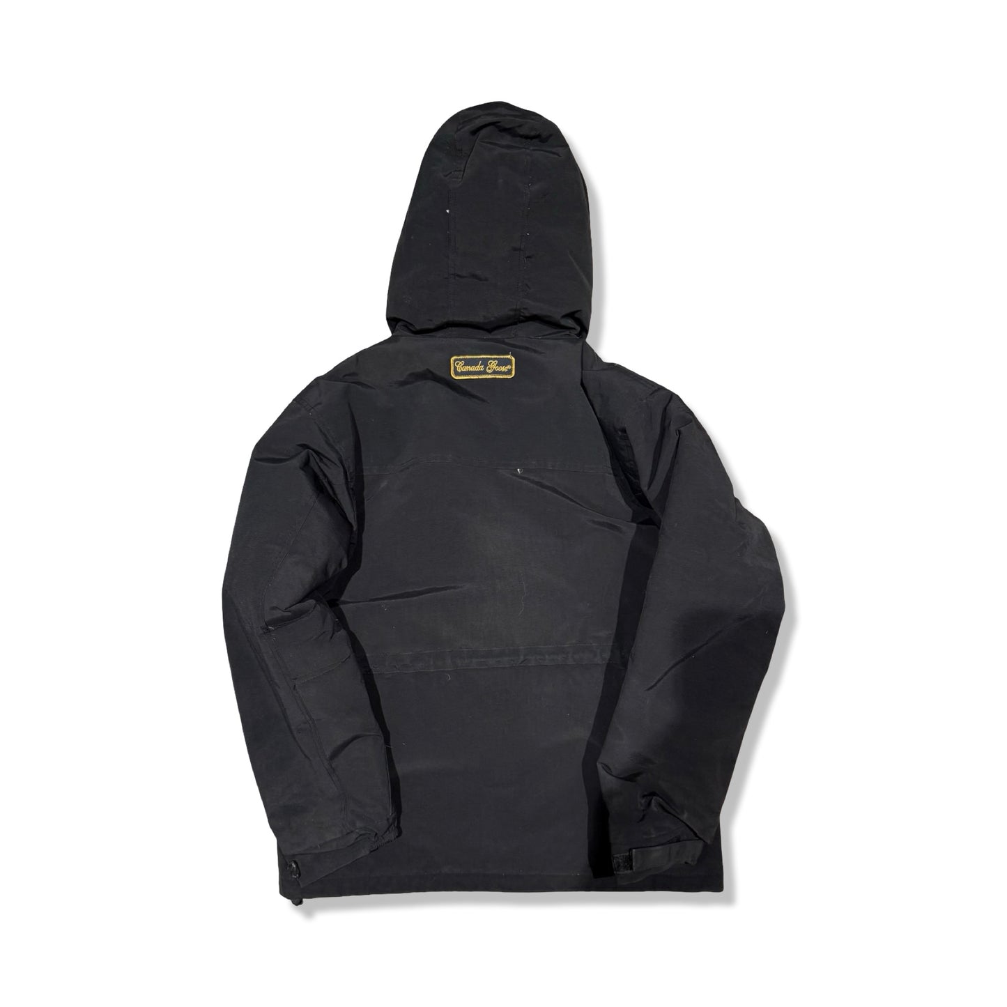 Baksidan av Canada Goose parkas för barn i svart, fotograferad mot en vit bakgrund.