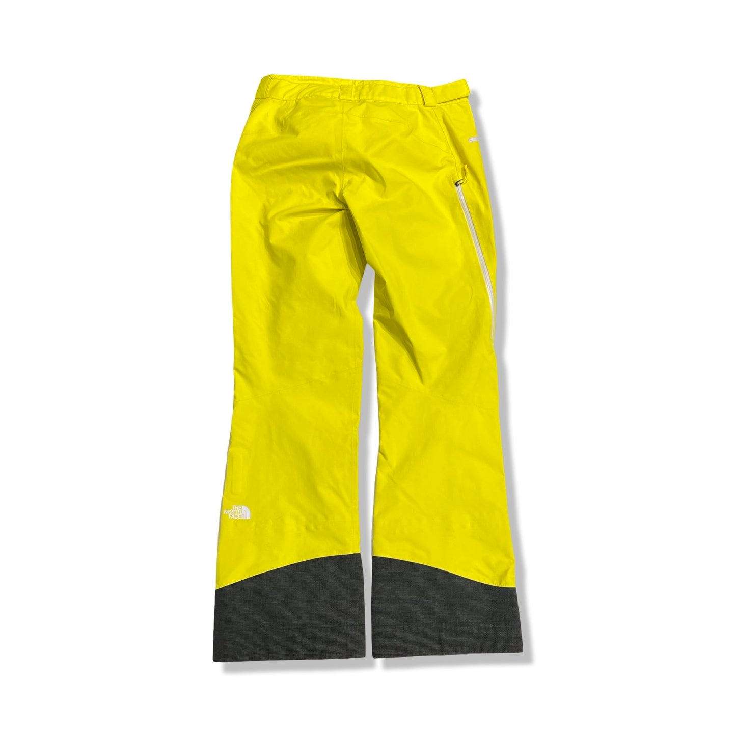 The North Face Summit Series GTX Pro skidbyxor för dam i gult och grått, fotograferade plant mot en vit bakgrund.