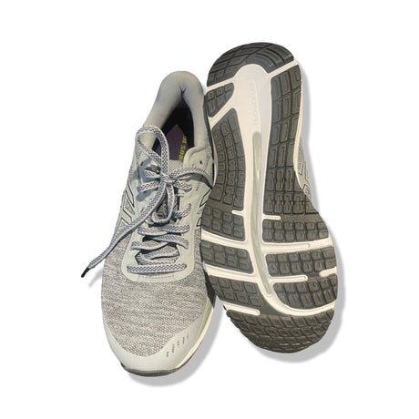 Asics GEL-Nimbus löparskor i blått, där ena skon visas uppifrån och den andra visar sulan mot en vit bakgrund.