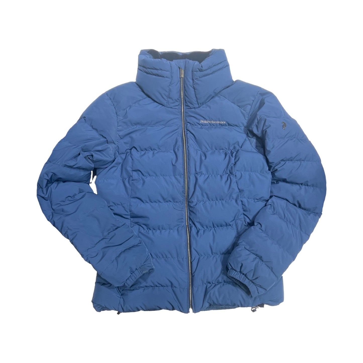 Peak Performance Velaero dunjacka för dam i blått. Jackan har en hög krage och heldragen dragkedja och är fotograferad platt mot en vit bakgrund.