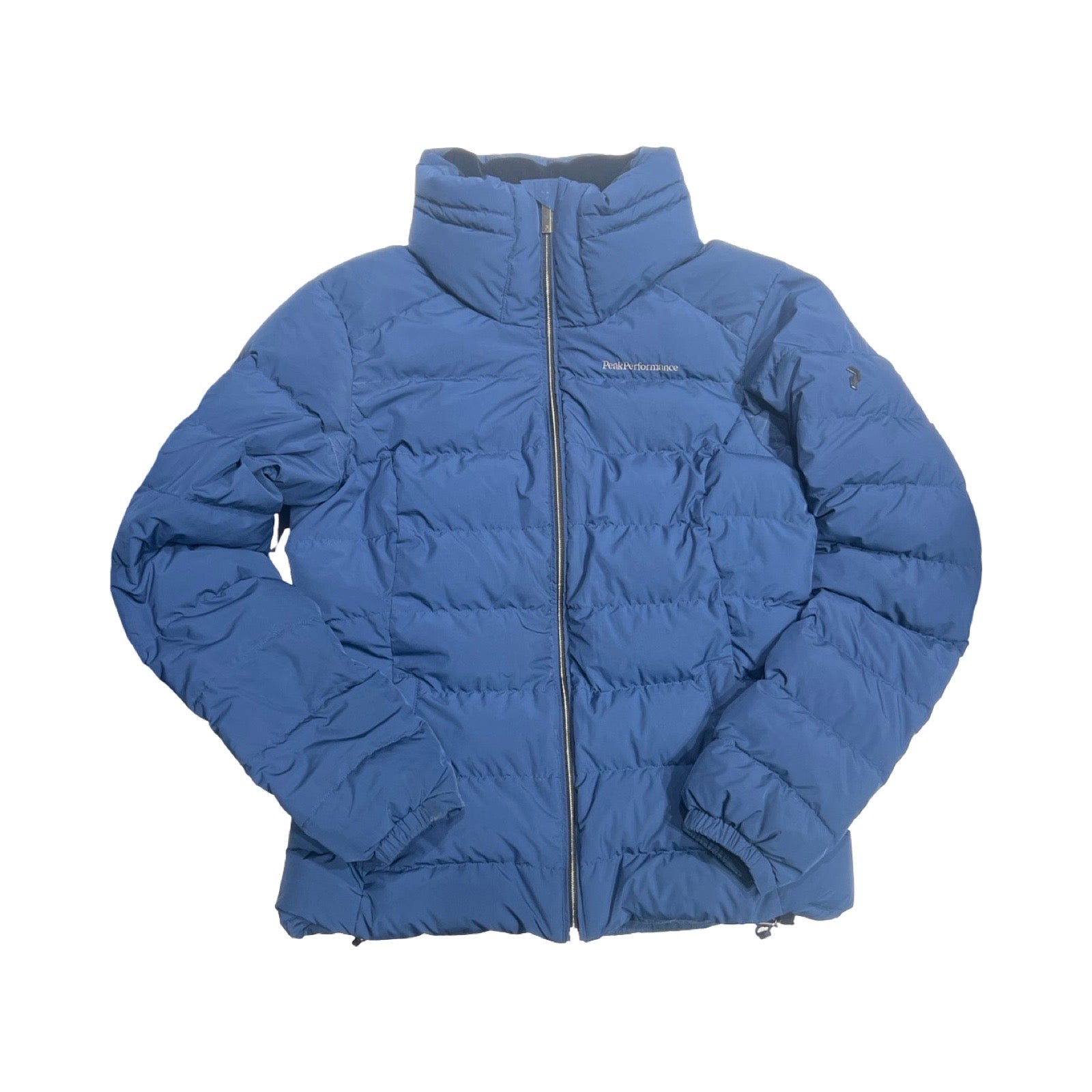 Peak Performance Velaero dunjacka för dam i blått. Jackan har en hög krage och heldragen dragkedja och är fotograferad platt mot en vit bakgrund.